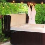 A hot tub is sitting under a canopy in the woods.