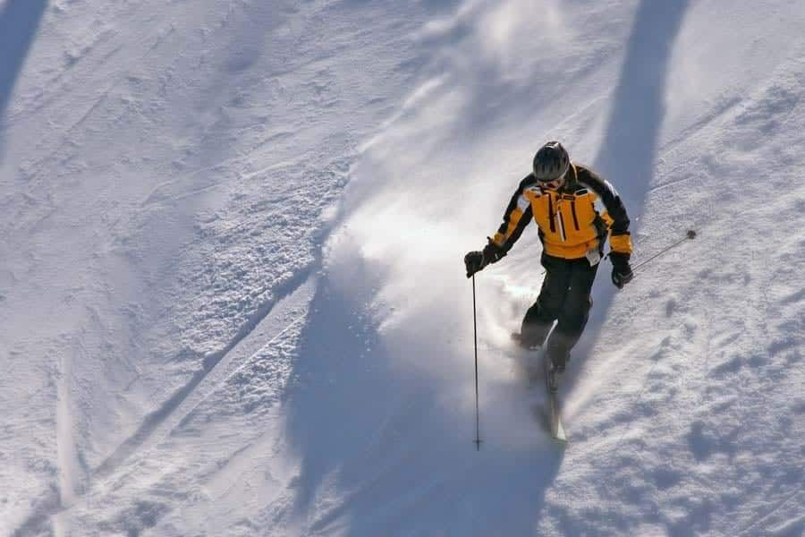 A man is skiing down a snow covered slope with the number 11 on his jacket