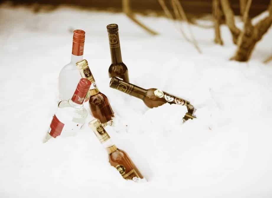 Three bottles of alcohol are laying in the snow