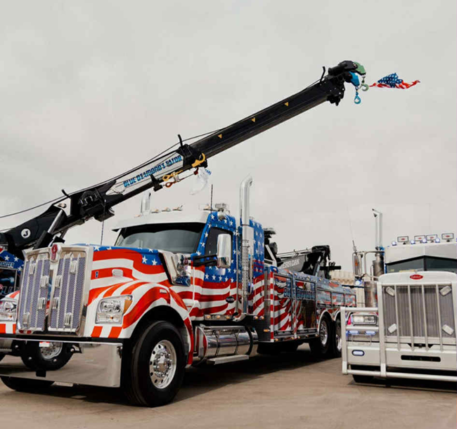 Front view of a black semi-truck with American flag design on snow.
