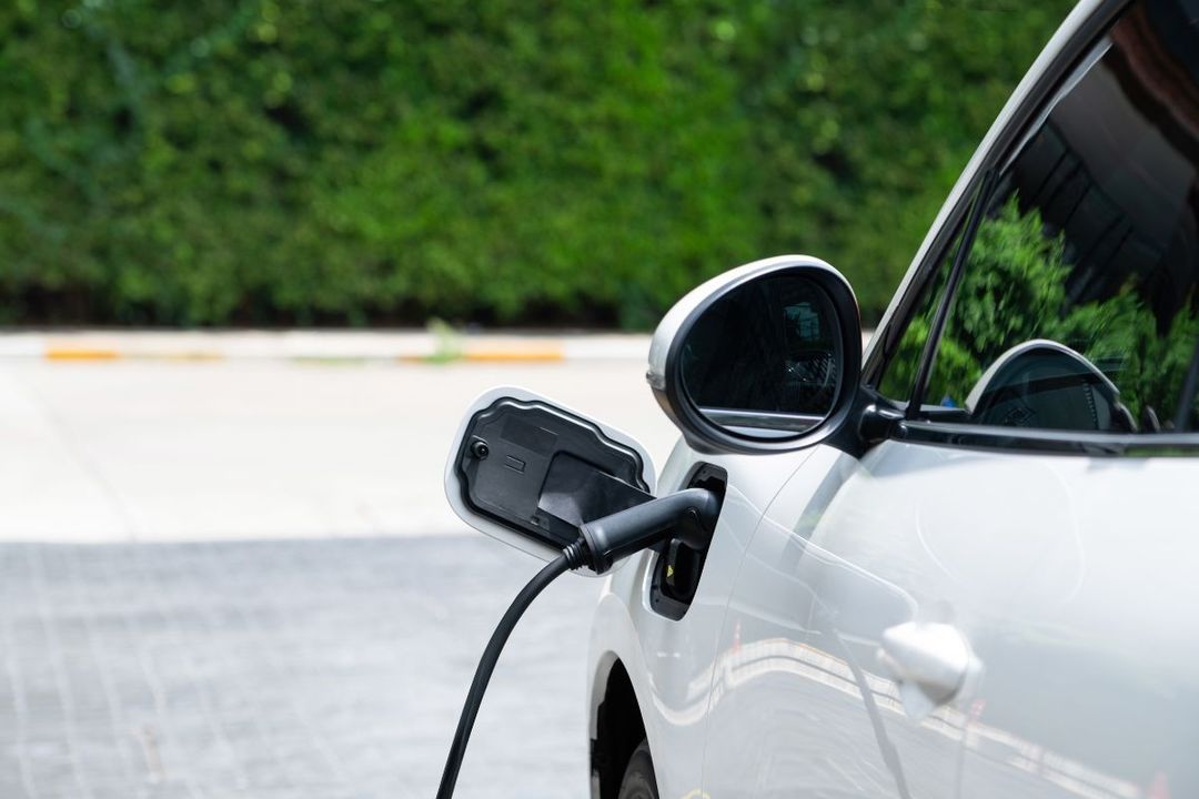 A woman plugging in her electric car with a nicely installed home EV charger.