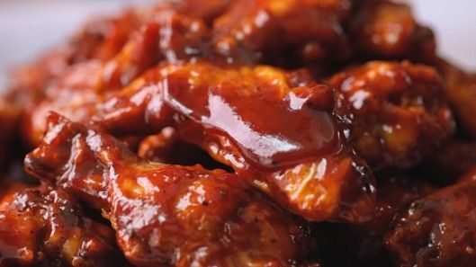 Close-up of chicken wings covered in a shiny, reddish-brown sauce.