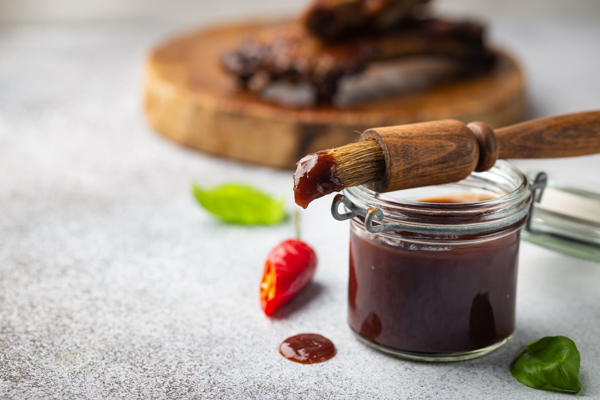 Barbecue sauce in glass jar with basting brush