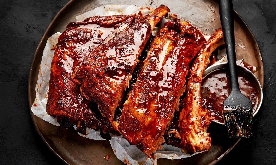 A plate of ribs with sauce and a fork on a table
