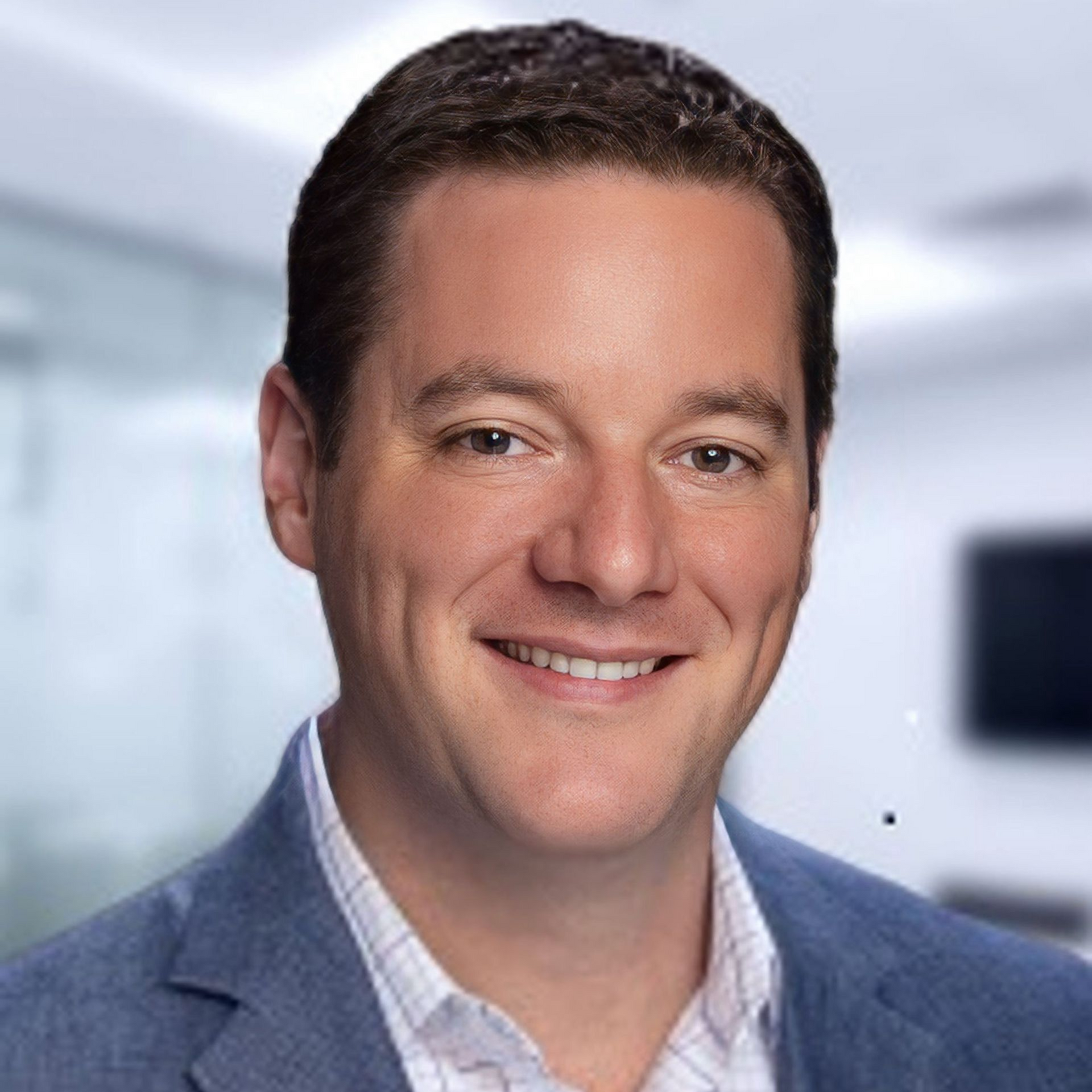 Smiling man in a blue blazer against a blurred office background