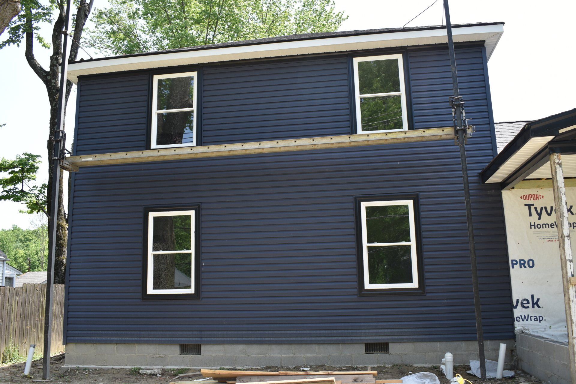 A blue house with white windows is being built.