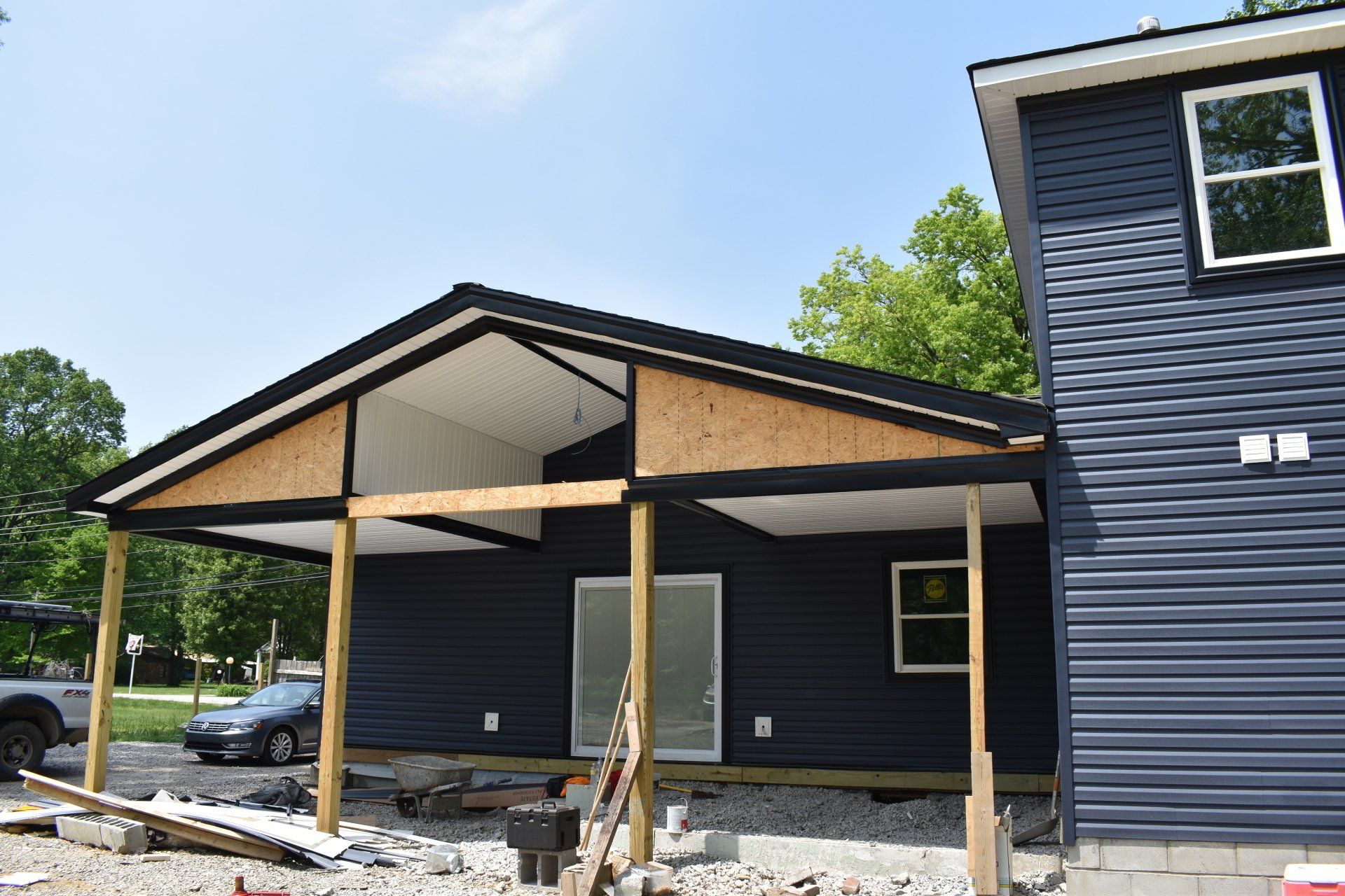 A blue house with a porch and a car parked in front of it.
