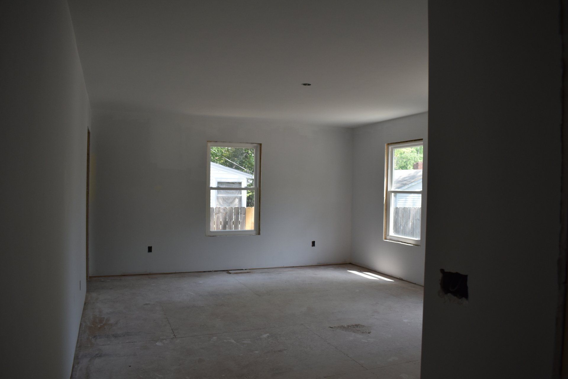An empty room with white walls and two windows