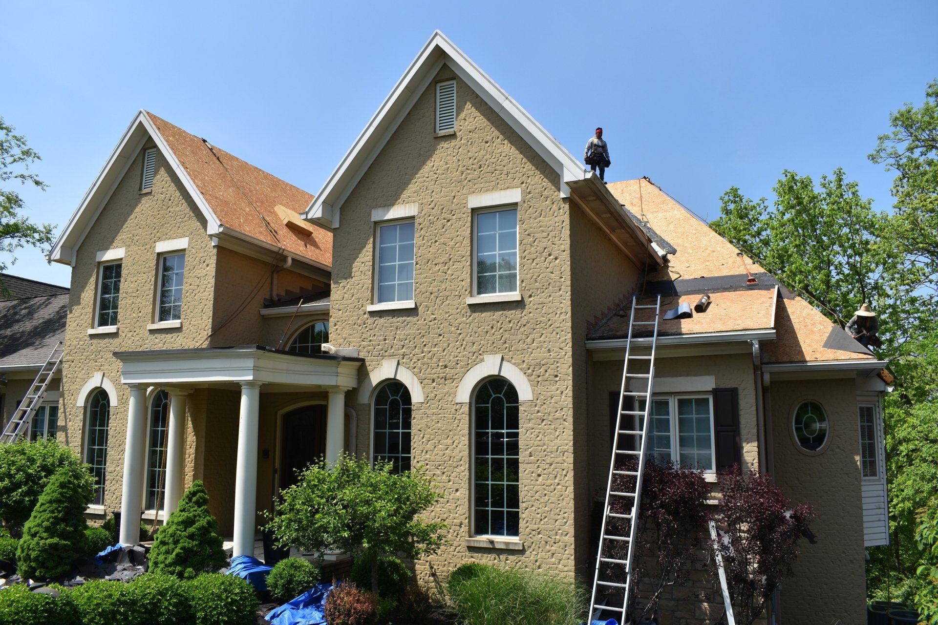 A large house with a ladder on the roof is being remodeled.