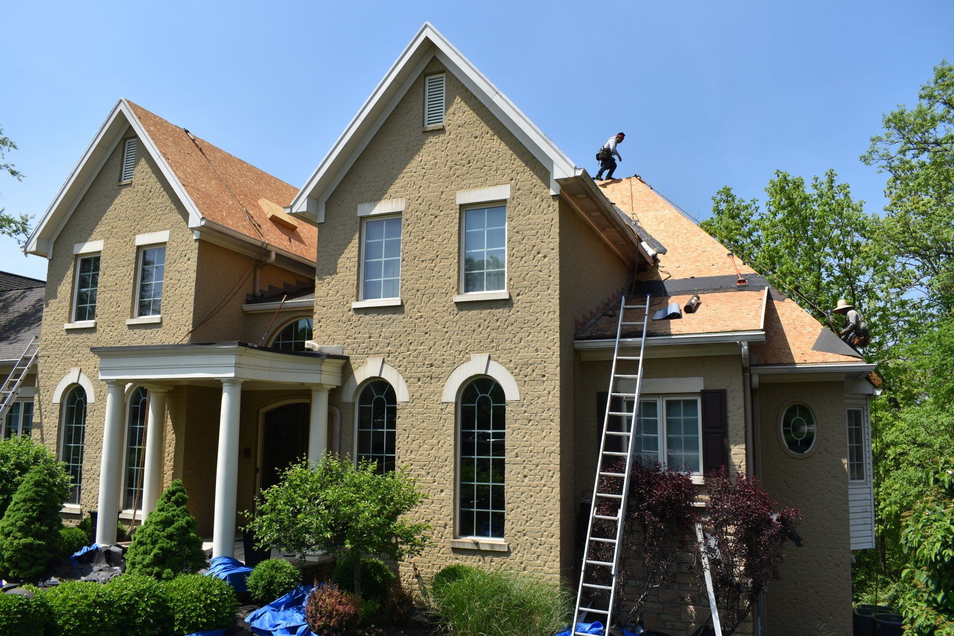 A man is working on the roof of a large house.