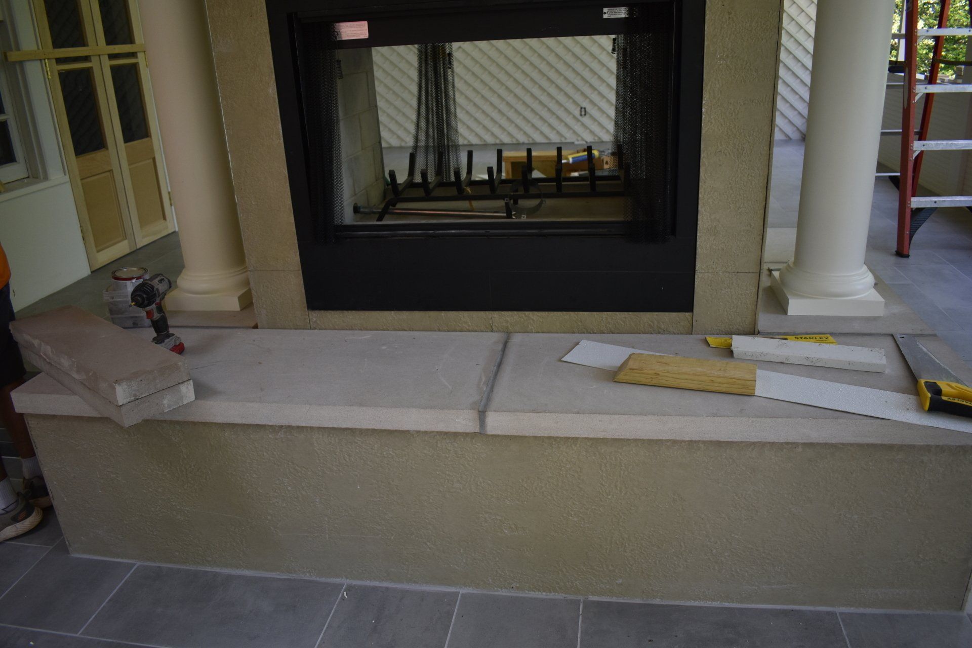 A man is working on a fireplace on a porch.