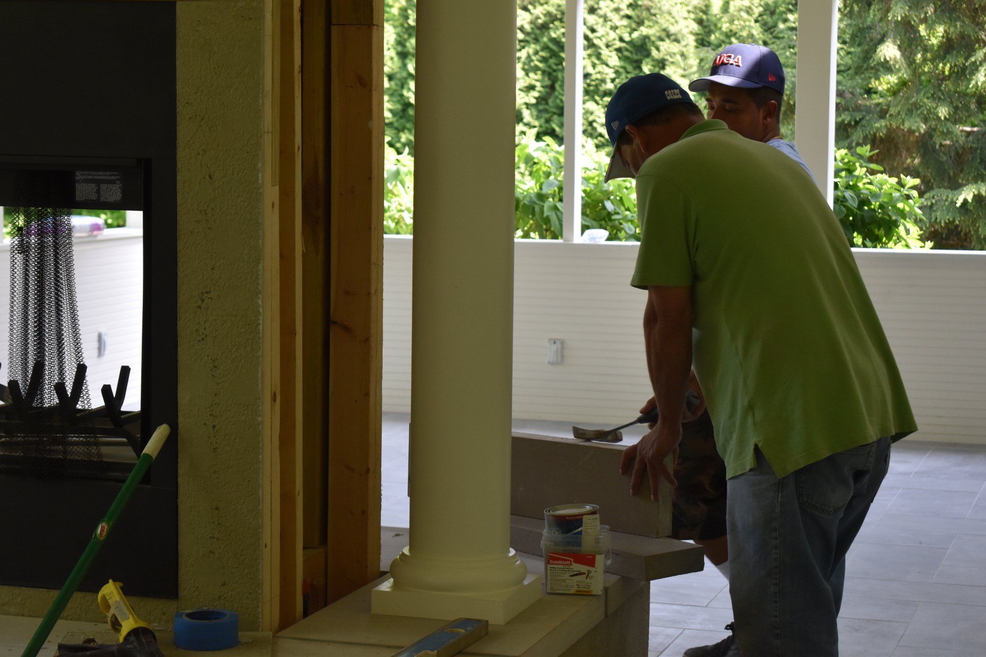 Two men are working on a fireplace in a living room