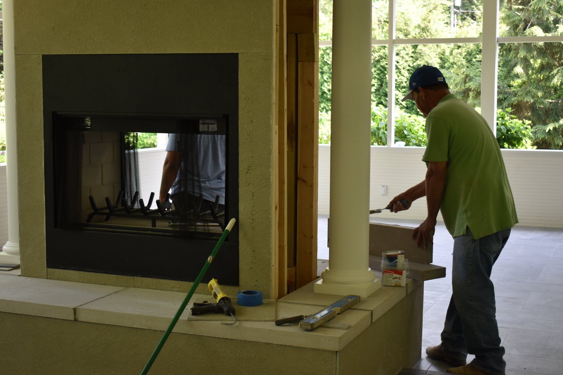 A man in a green shirt is working on a fireplace