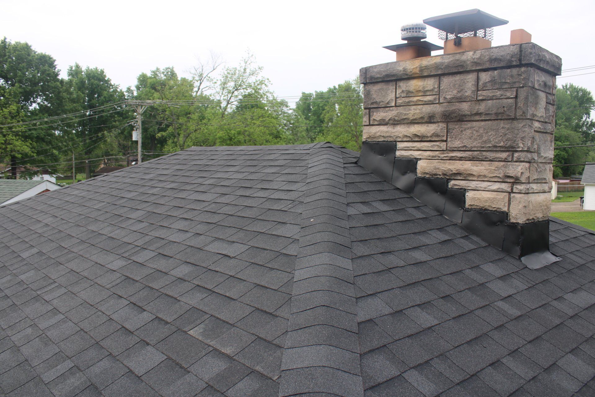 A roof with a chimney on top of it and trees in the background.
