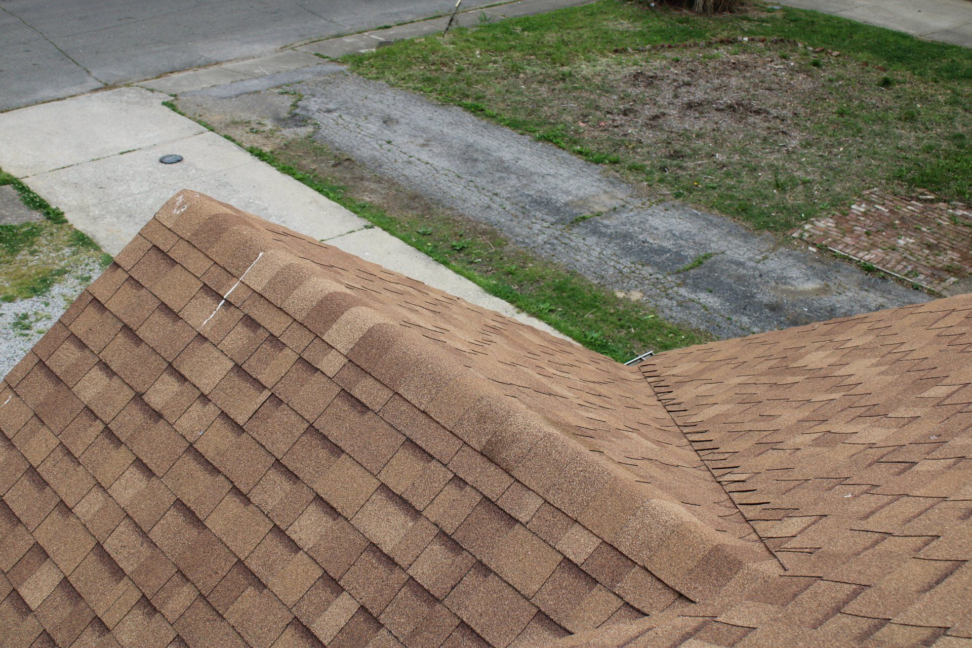 A brown roof is sitting on the side of a road next to a sidewalk.