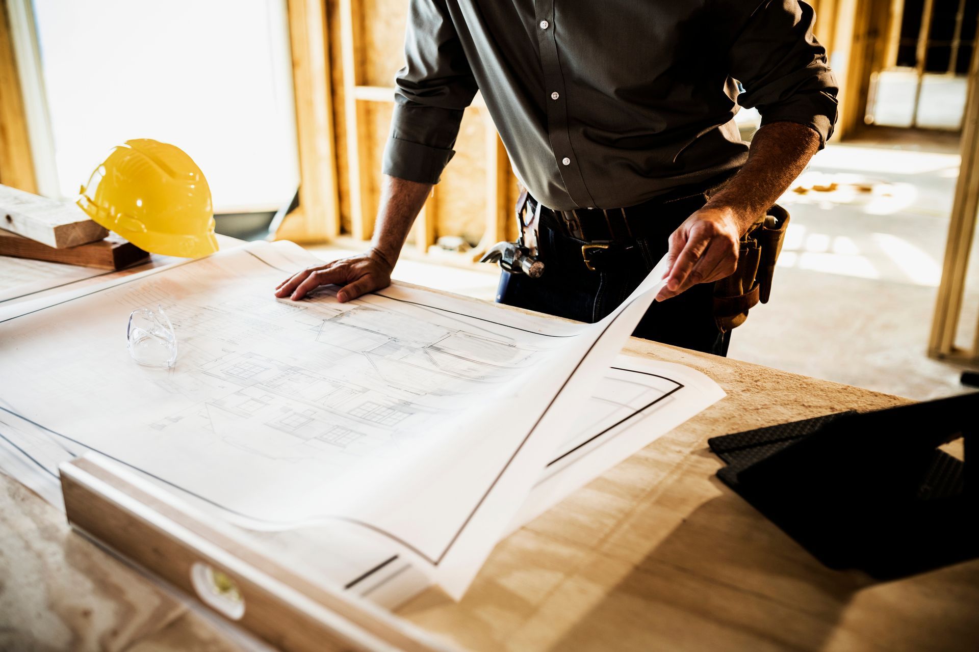A construction worker is looking at a blueprint on a table.