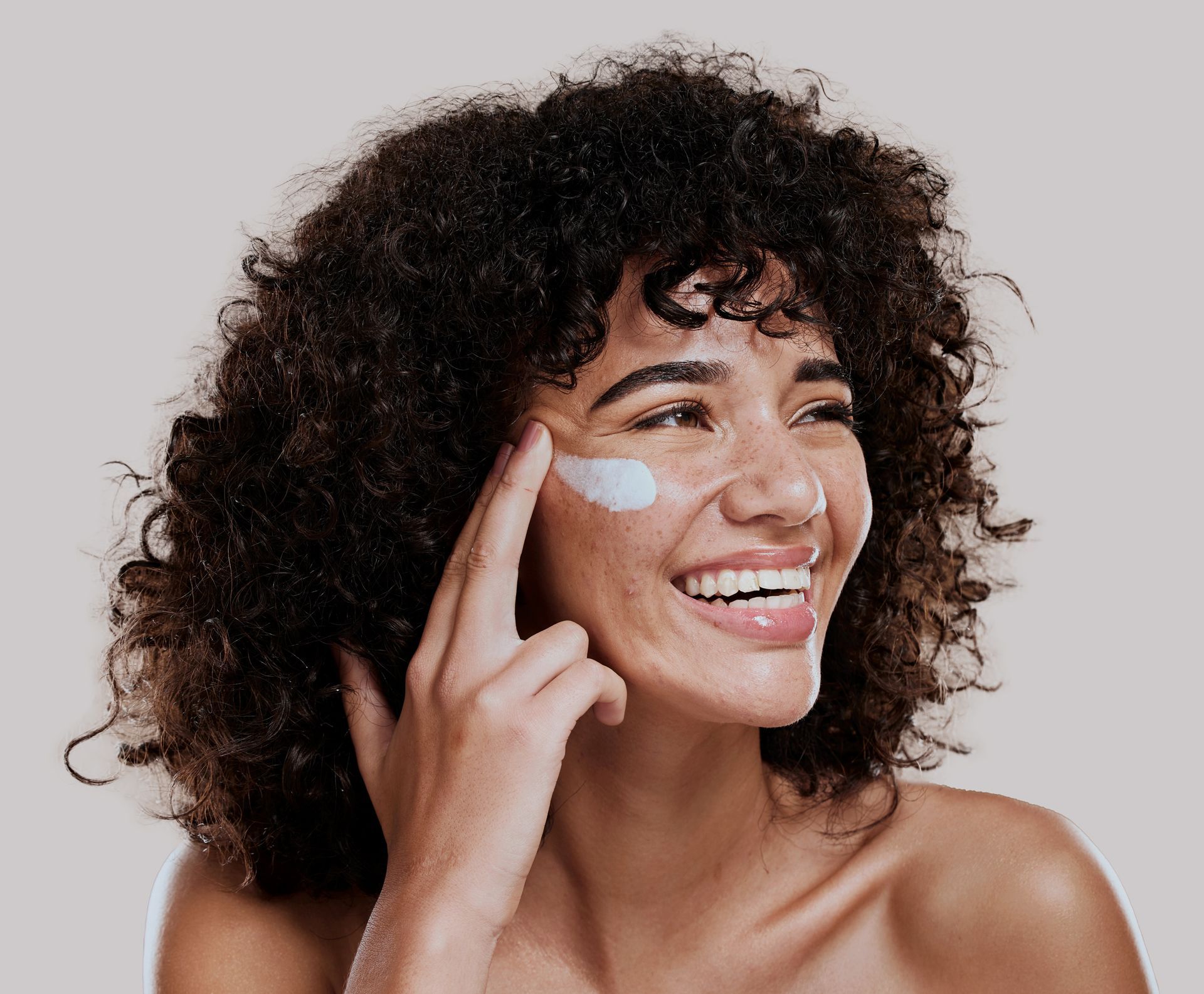 A woman applying cream to her face.