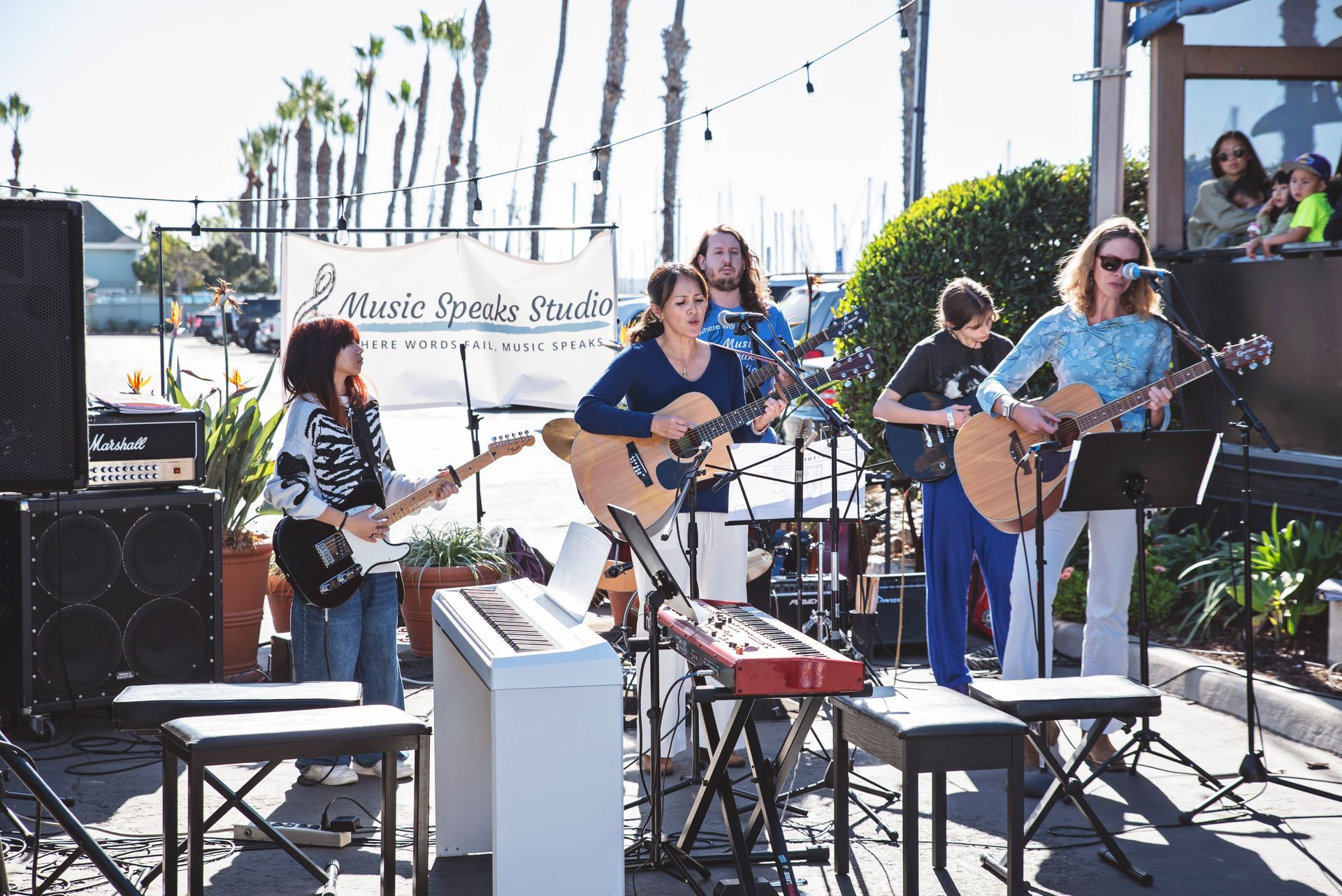 A group of people are playing guitars and keyboards on a stage.