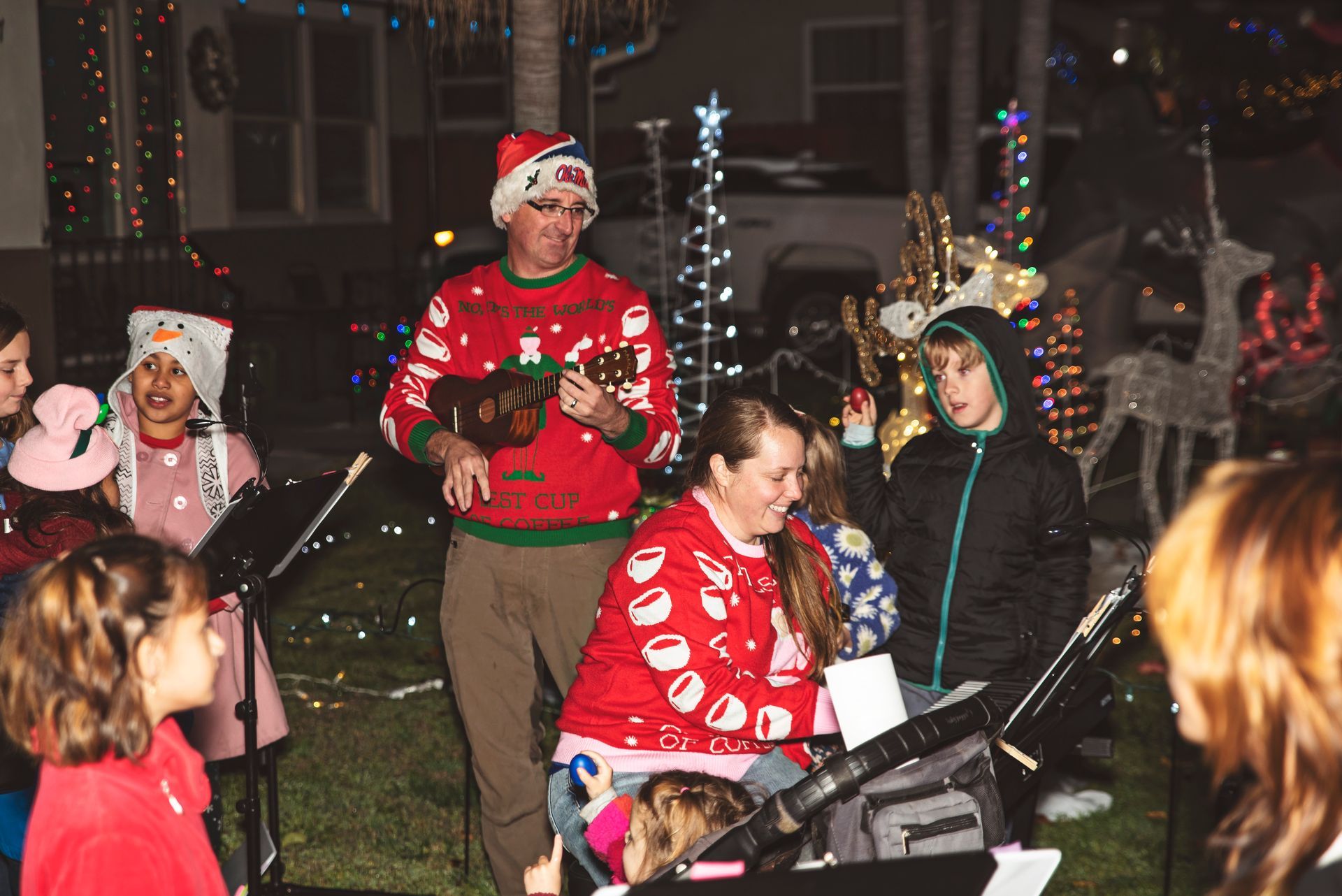 A group of people are singing christmas carols in front of a house.