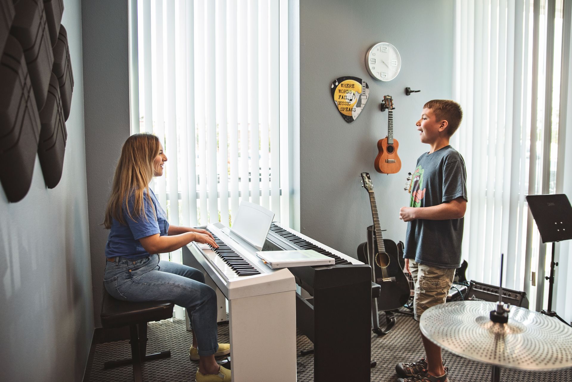 A woman is teaching a boy how to play the piano.