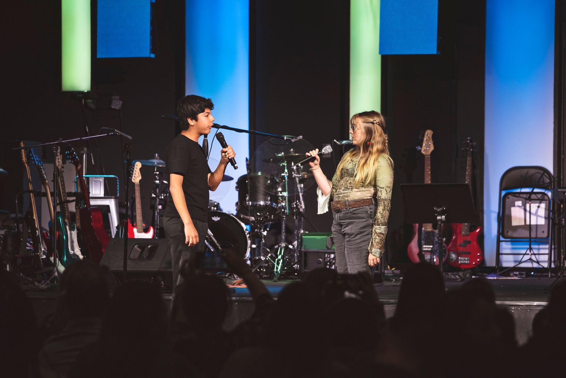 A man and a woman are singing into microphones on a stage.