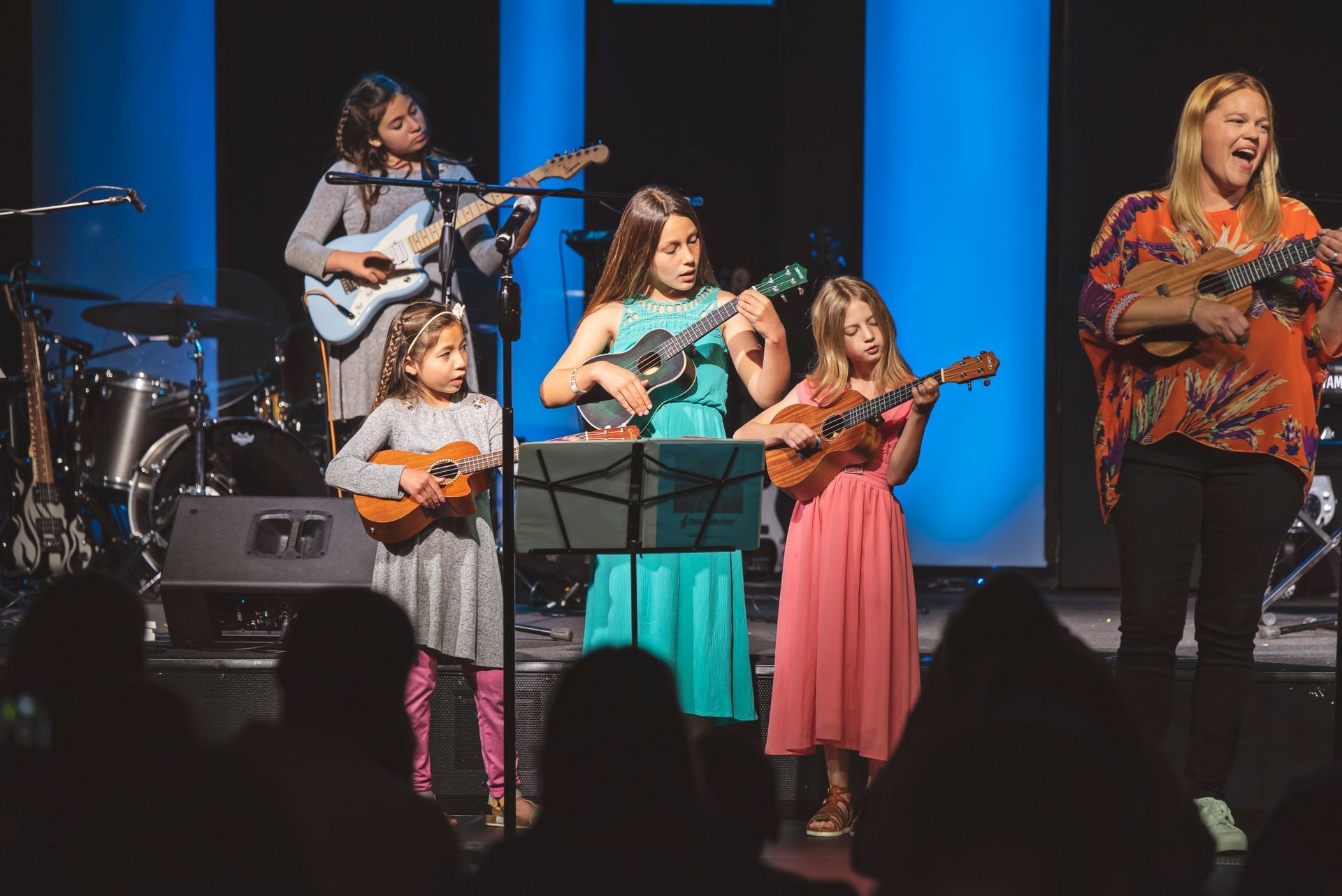 A group of young girls are playing ukuleles on a stage.