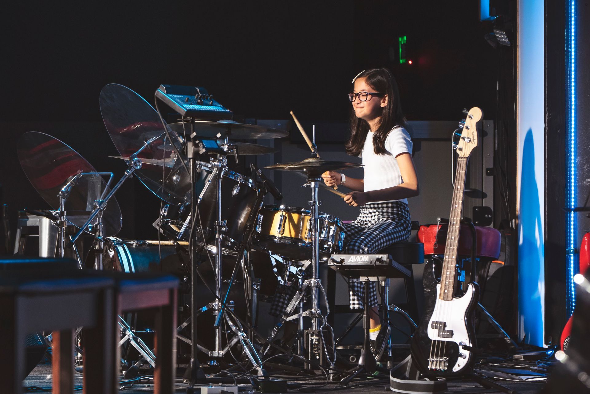 A young man is playing drums in a room.