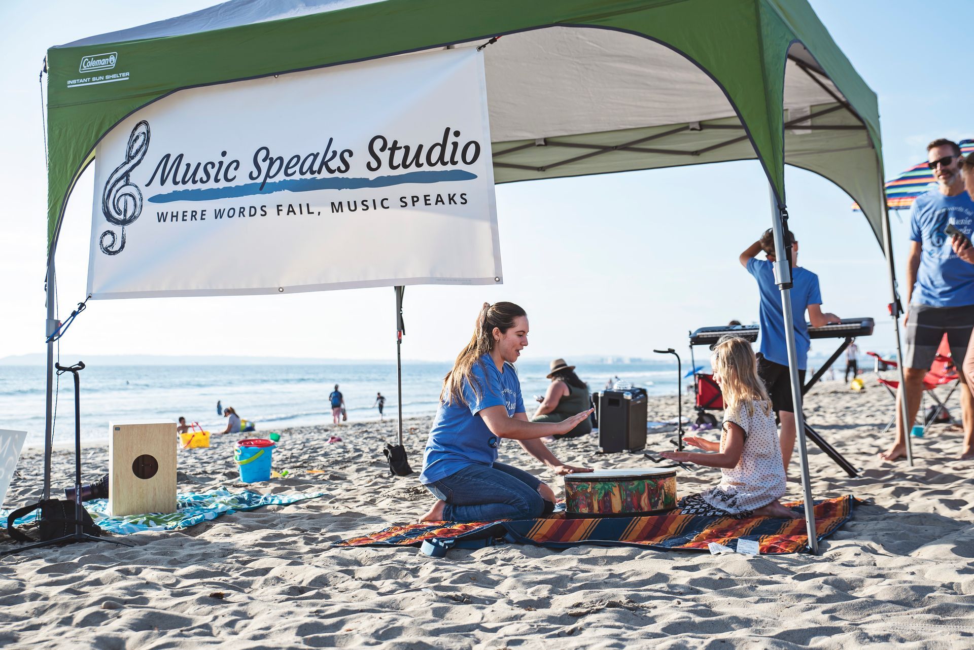 A group of people are sitting under a tent on the beach.