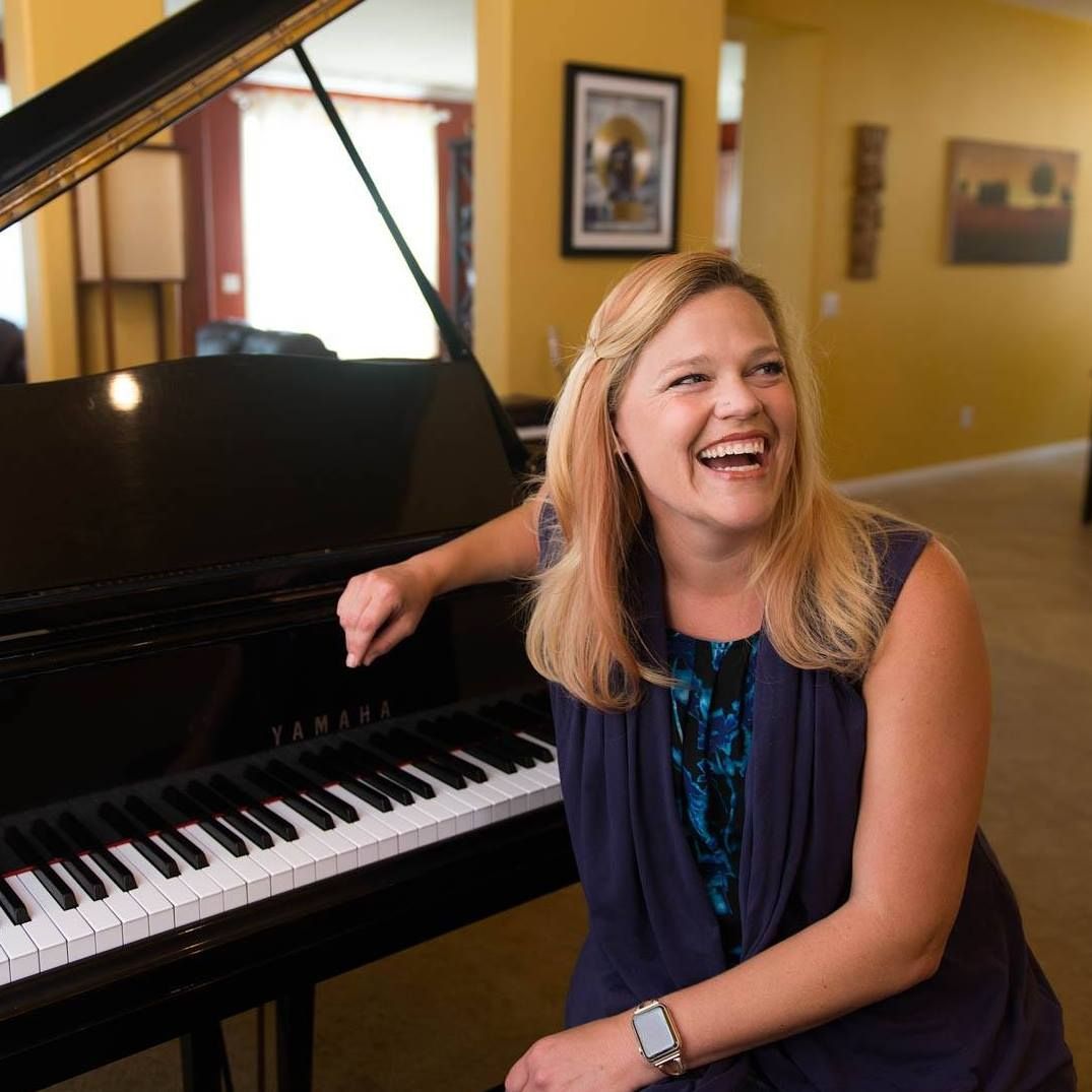 A woman is sitting in front of a piano and smiling