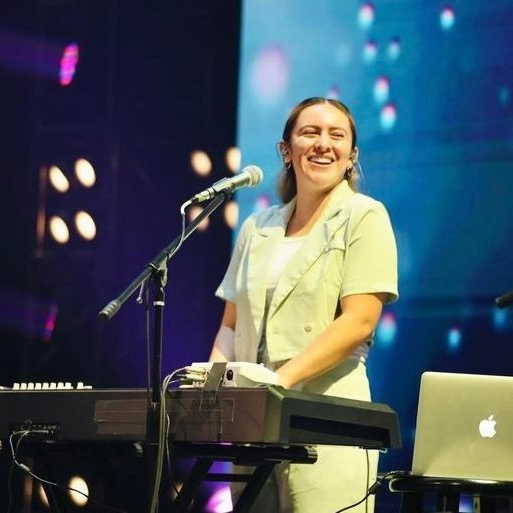 A woman is sitting in front of a piano and smiling