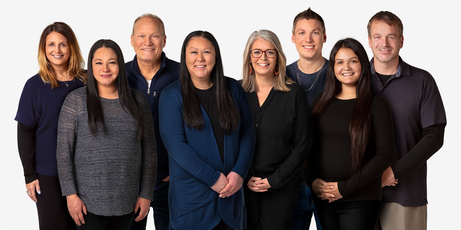 Group photo of diverse people, standing close together, smiling, against a white background.