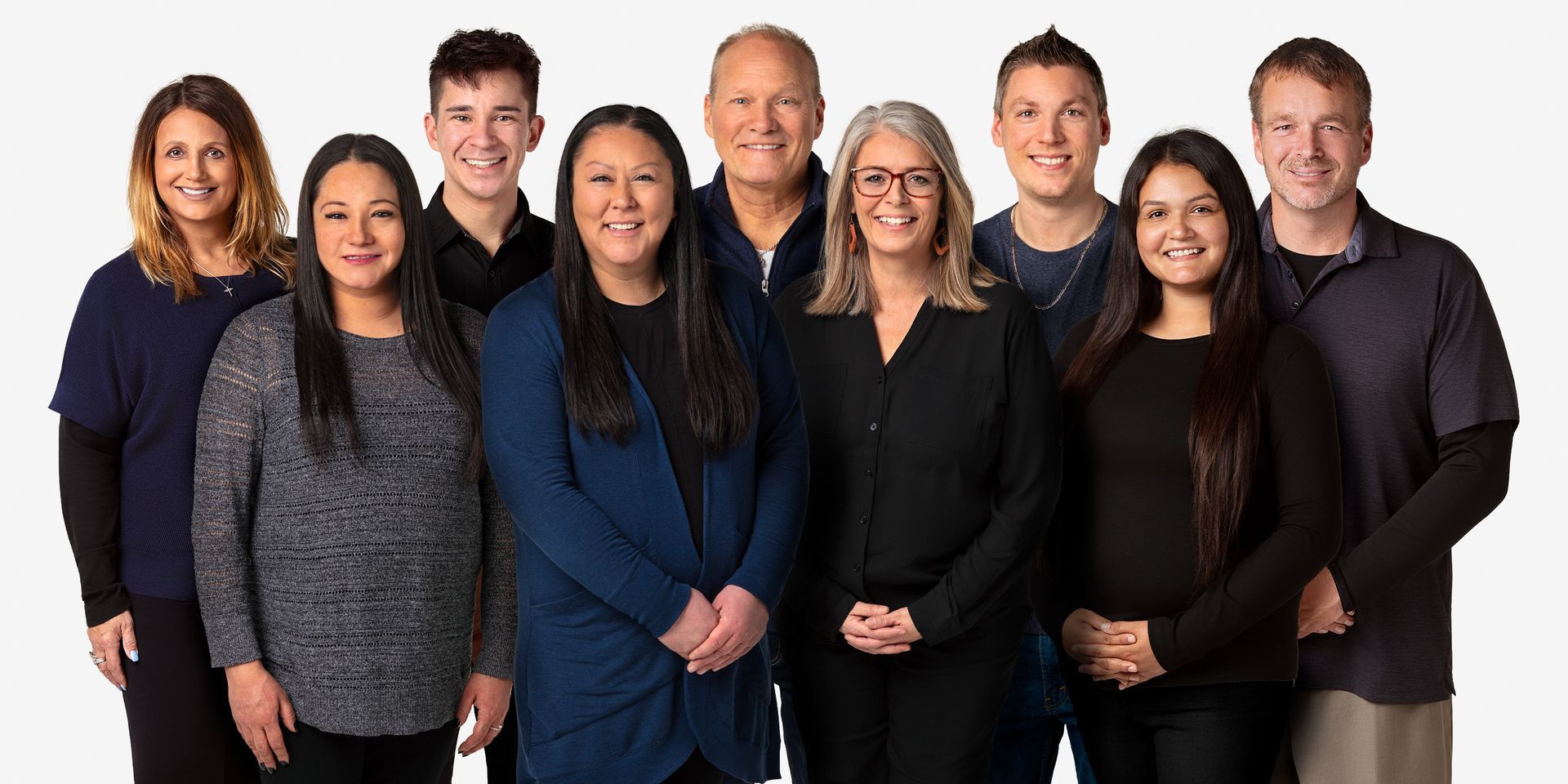 Group photo of diverse people, standing close together, smiling, against a white background.