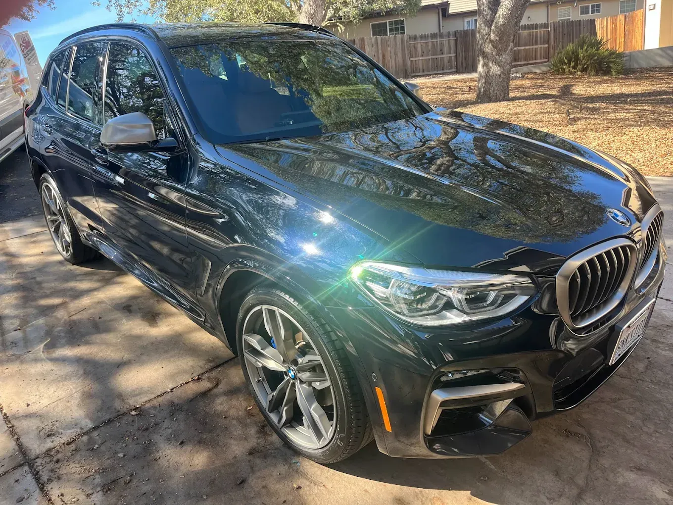 Dark blue BMW X3 SUV parked outdoors, shiny in sunlight.
