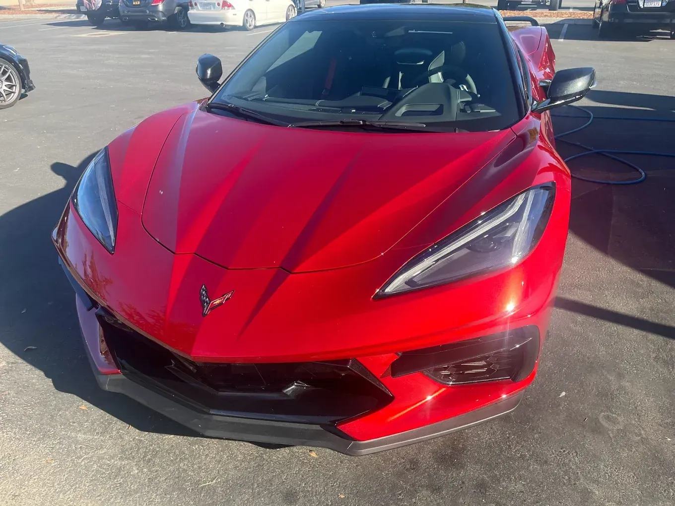 Red Chevrolet Corvette sports car parked outdoors on a sunny day.