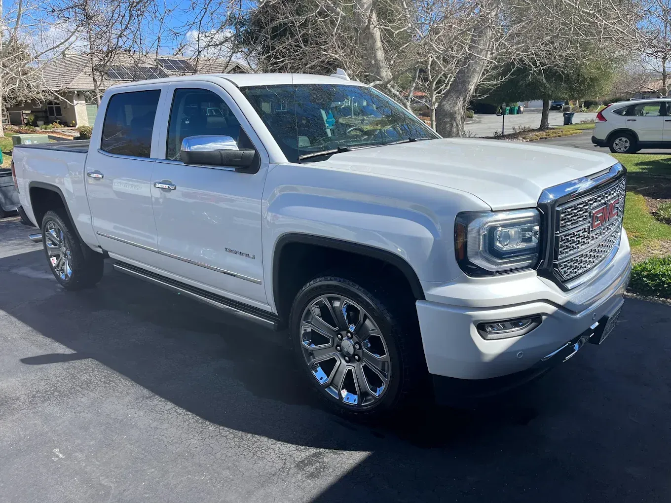 White GMC Sierra pickup truck parked on asphalt driveway.