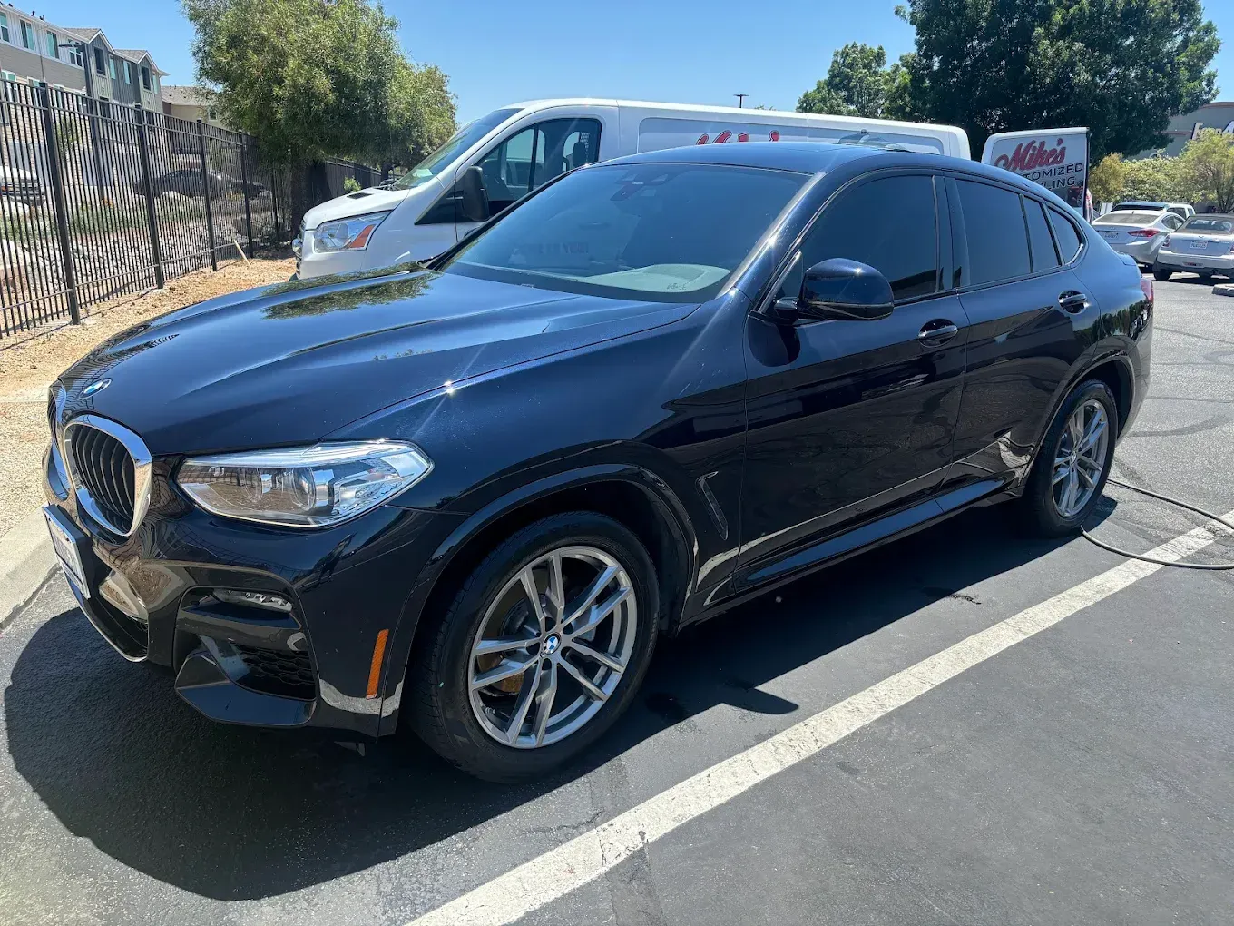 Black BMW SUV parked in a parking lot on a sunny day.