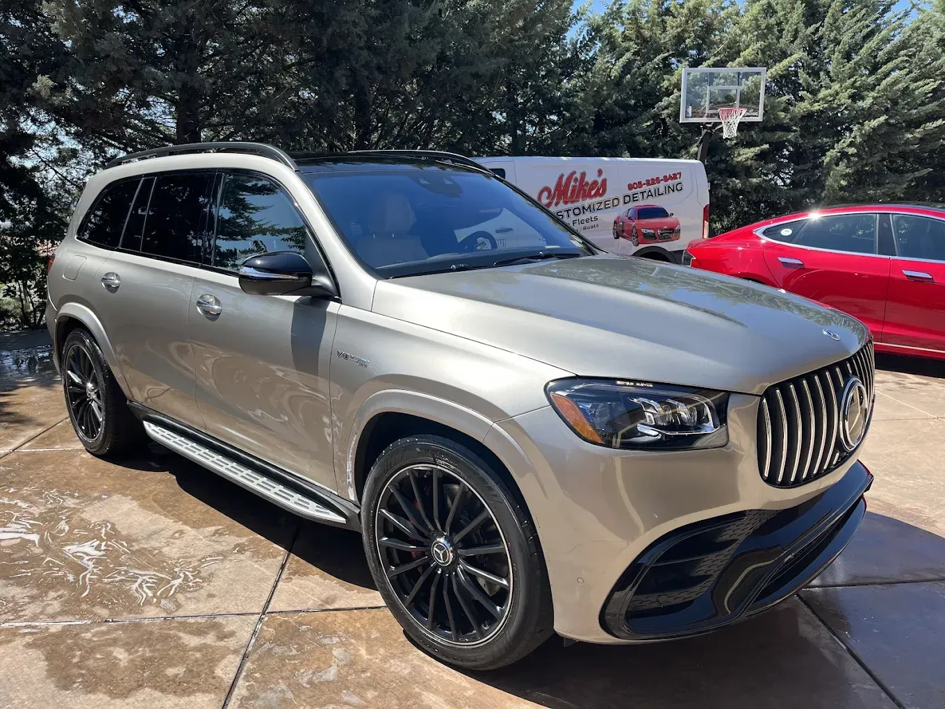 Gold SUV parked on a concrete driveway with black rims.  A logo for 