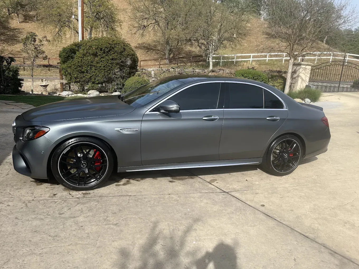 Gray Mercedes-AMG E 63 S sedan with tinted windows and black rims parked on a driveway.