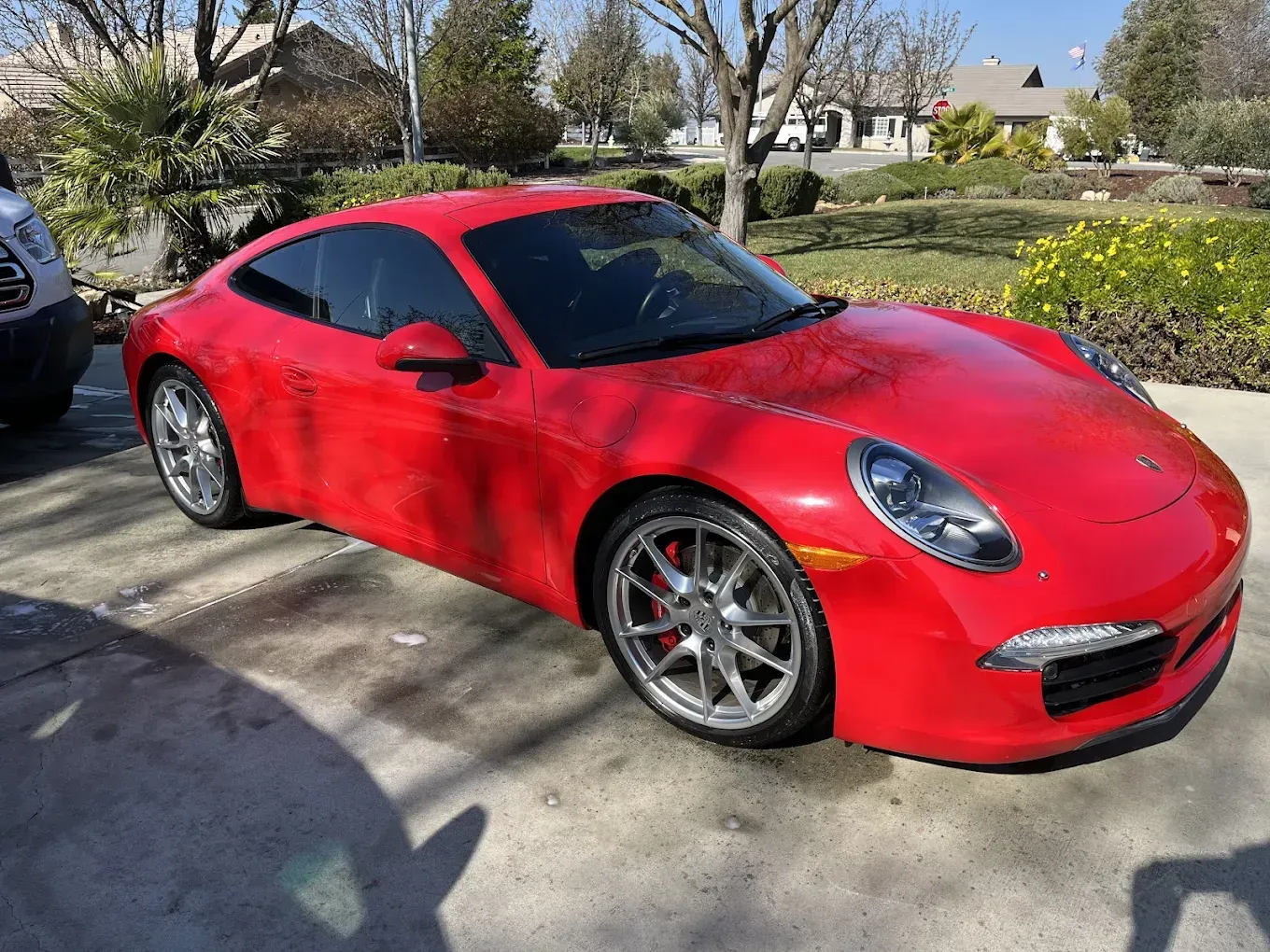 Red Porsche sports car parked on a driveway in a residential area.