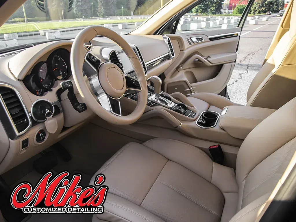 Beige interior of a luxury SUV, featuring leather seats, a steering wheel, and a center console.