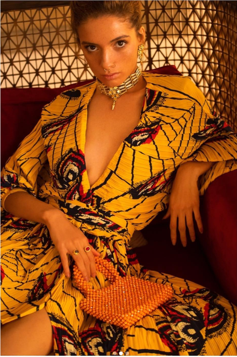 Une femme en robe jaune est assise sur un canapé rouge