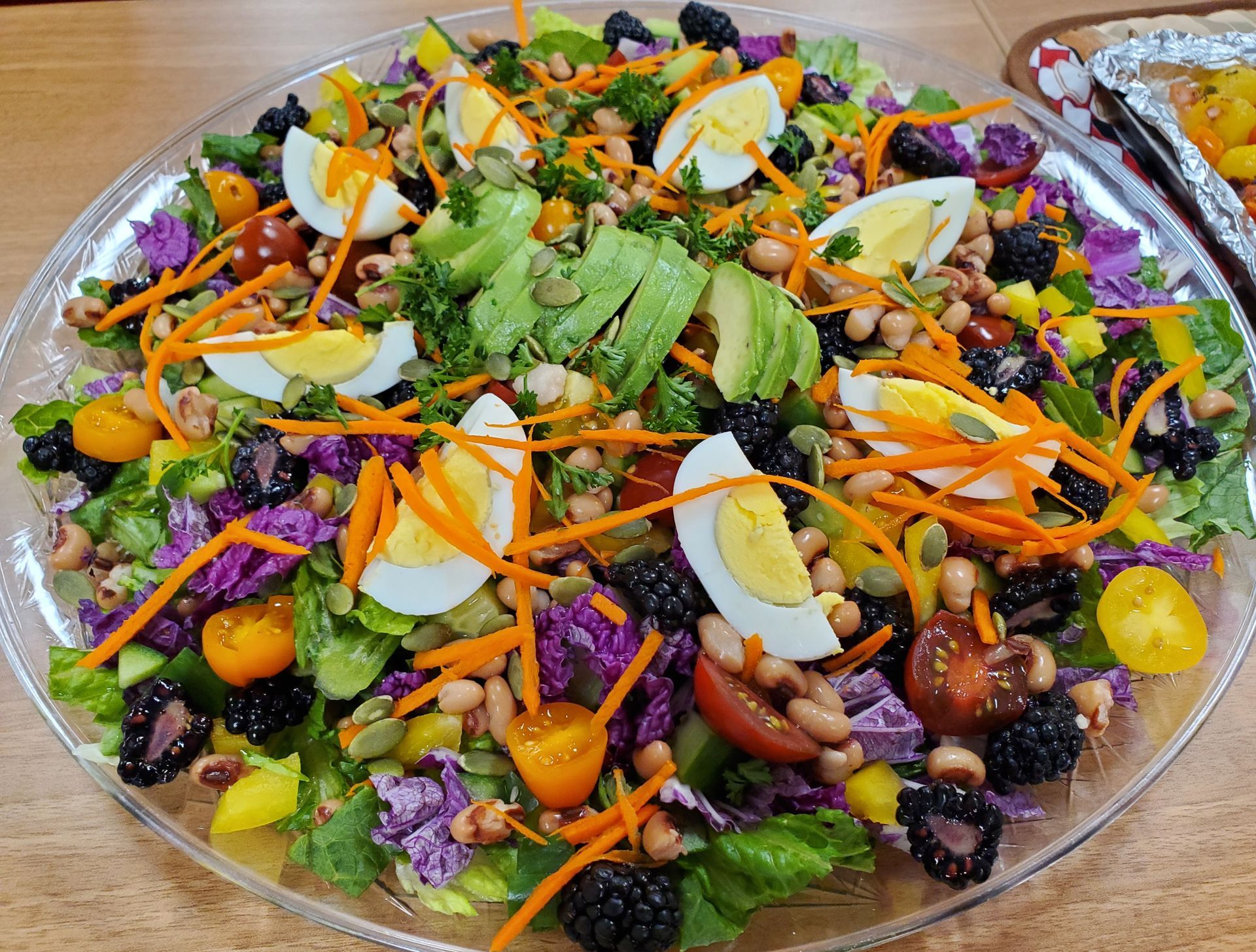 A salad with eggs , black eyed peas , avocado , carrots and other vegetables on a plate.