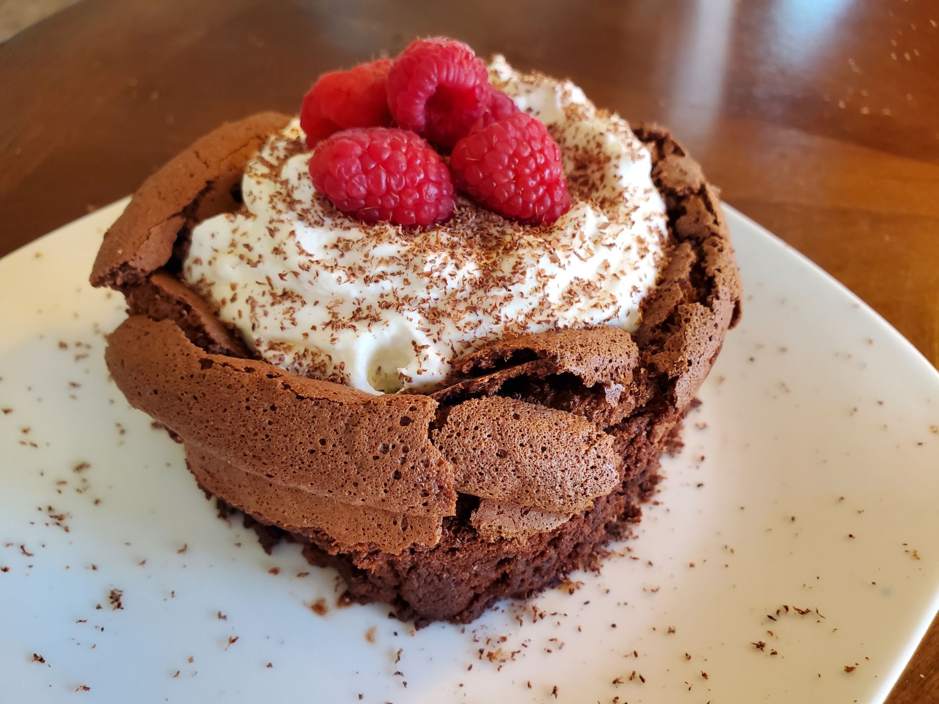 A brownie with whipped cream and raspberries on top