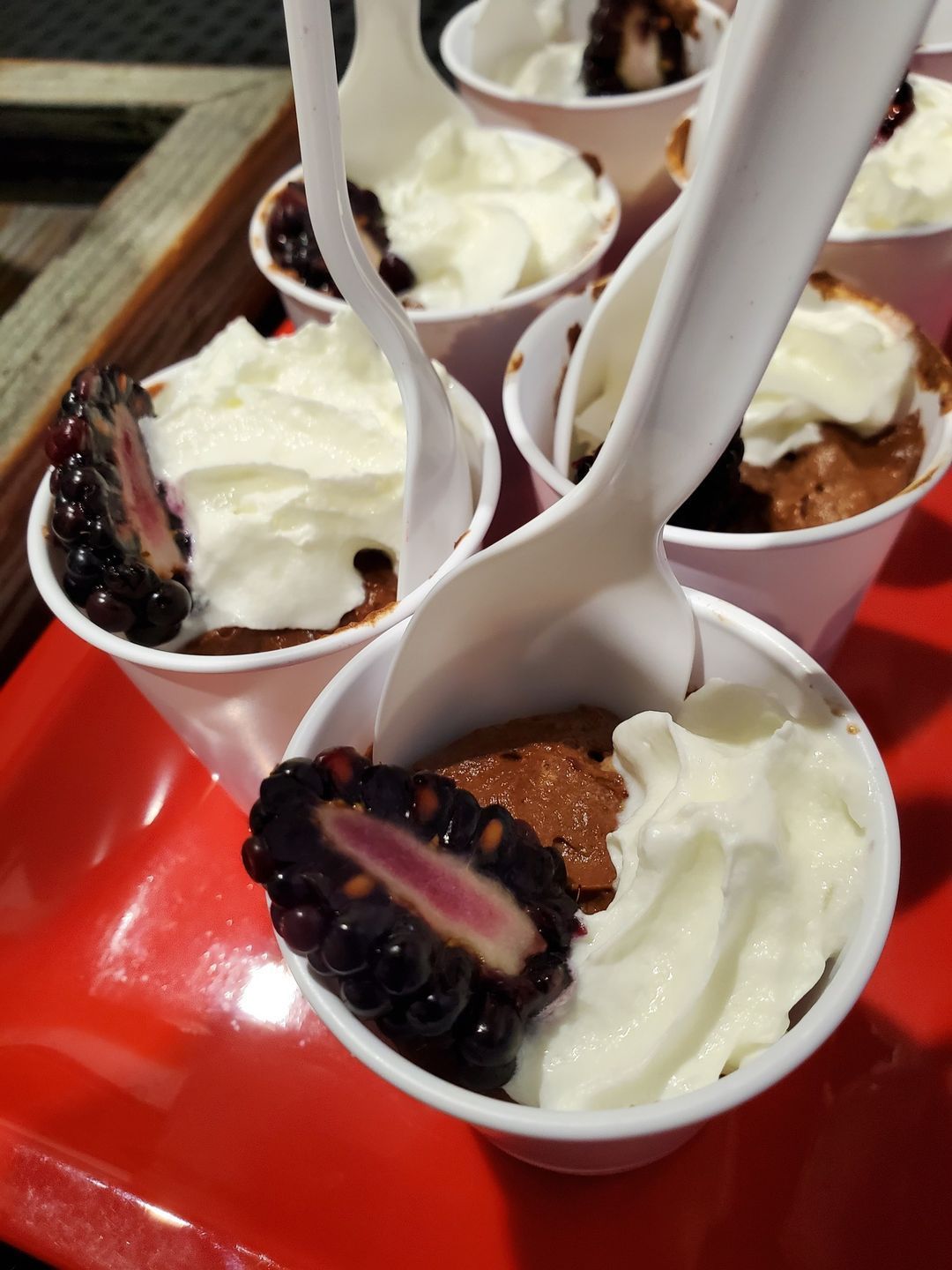 Four bowls of dessert with spoons in them on a red tray