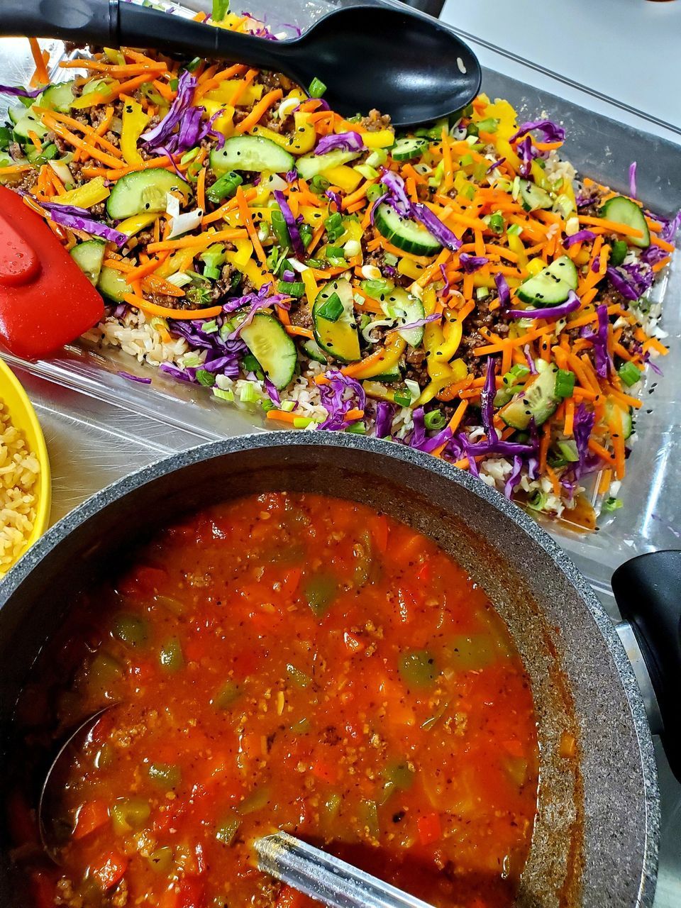 A tray of vegetables and a pot of sauce on a table.