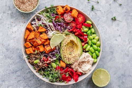 Colorful vegan bowl with sweet potatoes, avocado, and vegetables.