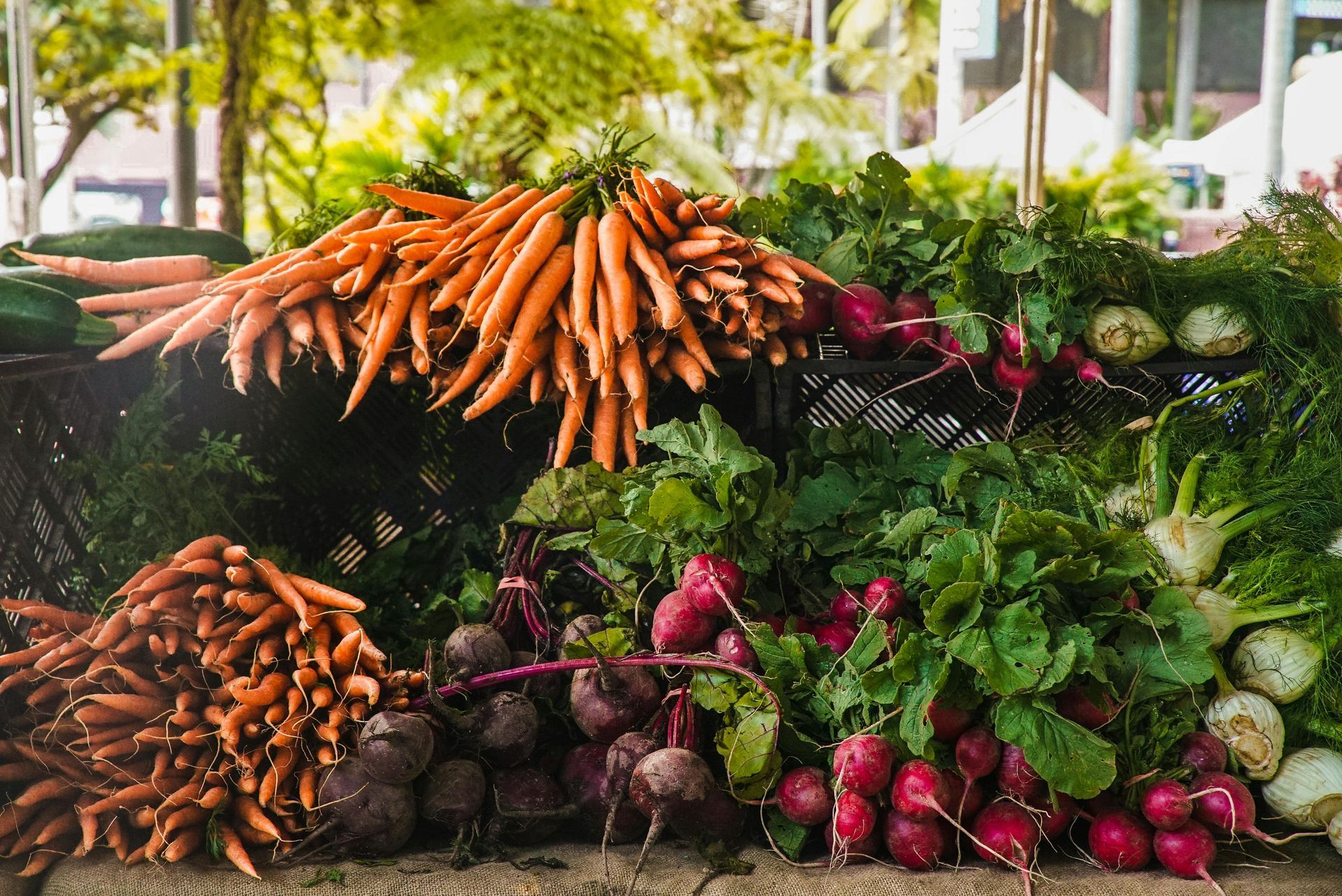 Carrots, beets, and radishes piled on a market display, vibrant colors.