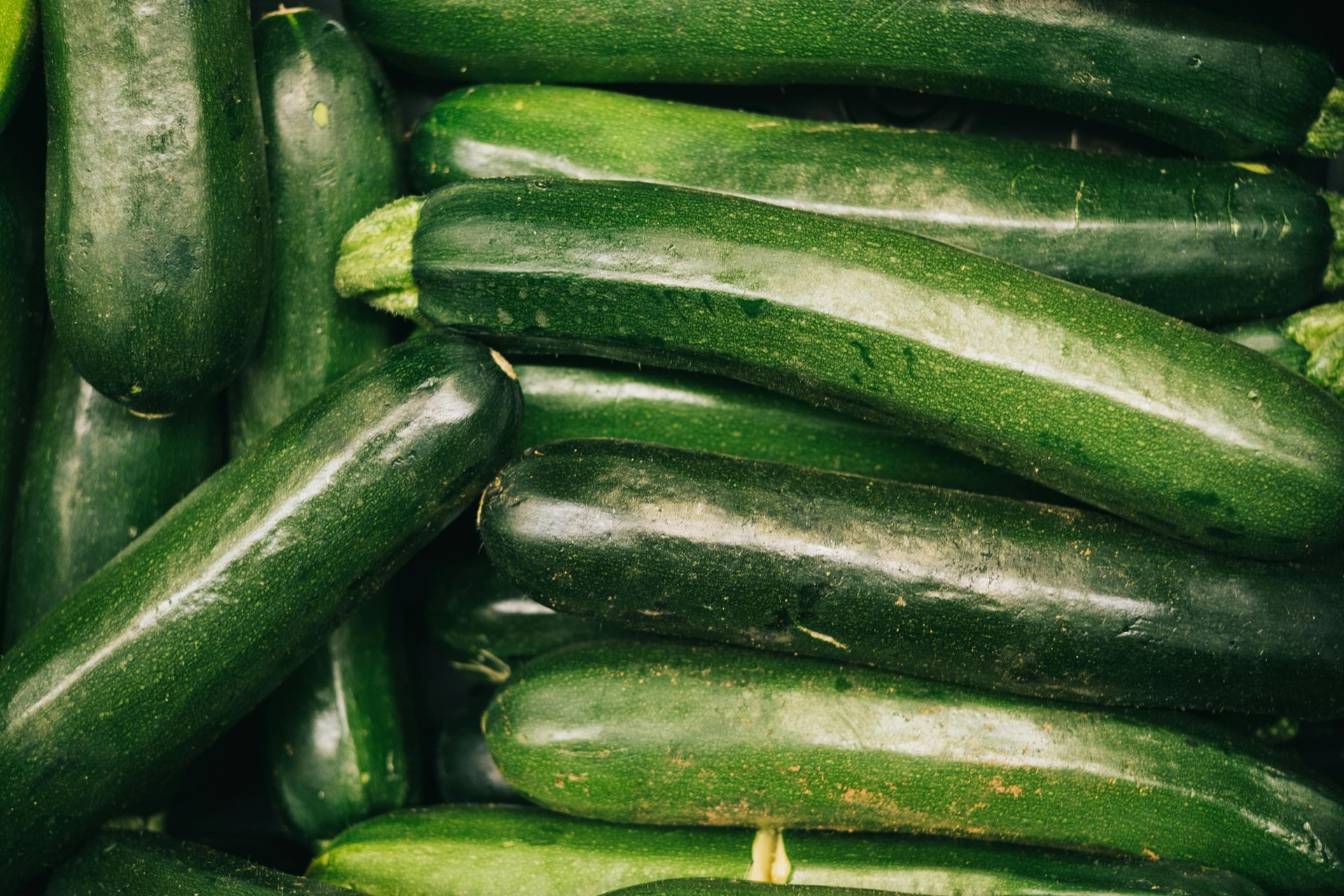 A pile of green zucchini sitting on top of each other on a table.