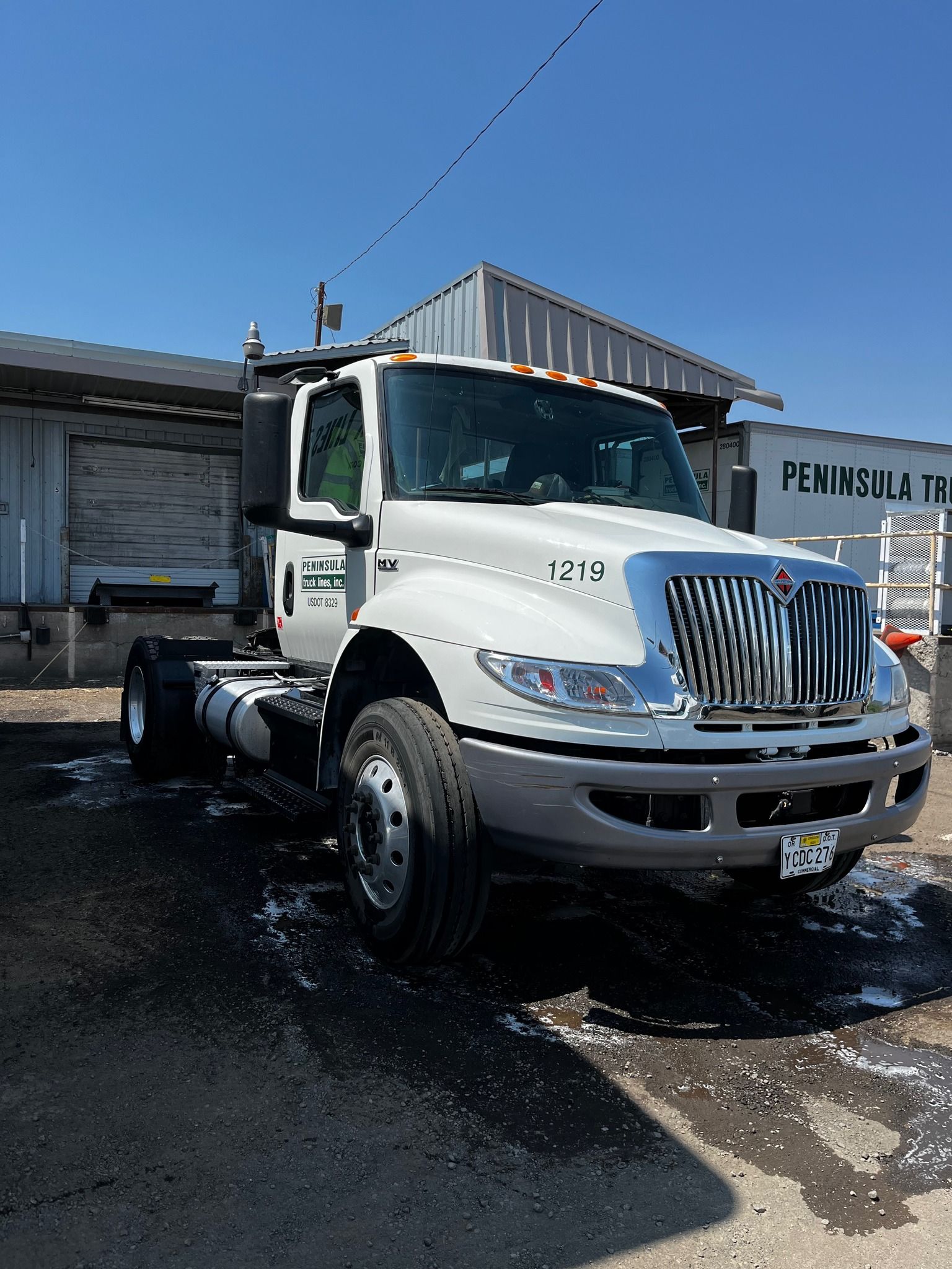 White International truck with a chrome grill parked in front of a building on a sunny day. 