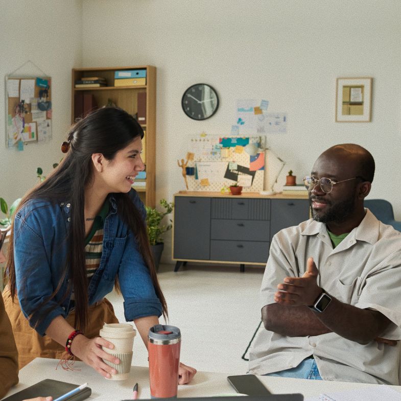 Woman with long, wavy brown hair, outdoors in front of bare tree branches, wearing brown coat, side profile.